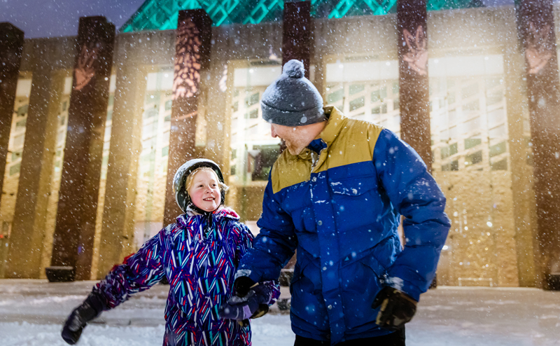 A father and daughter holding hands while skating at Churchill Square.
