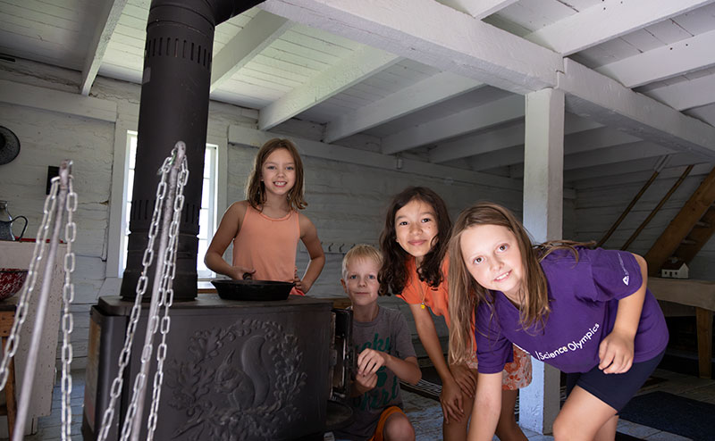 children in kitchen beside antique stove