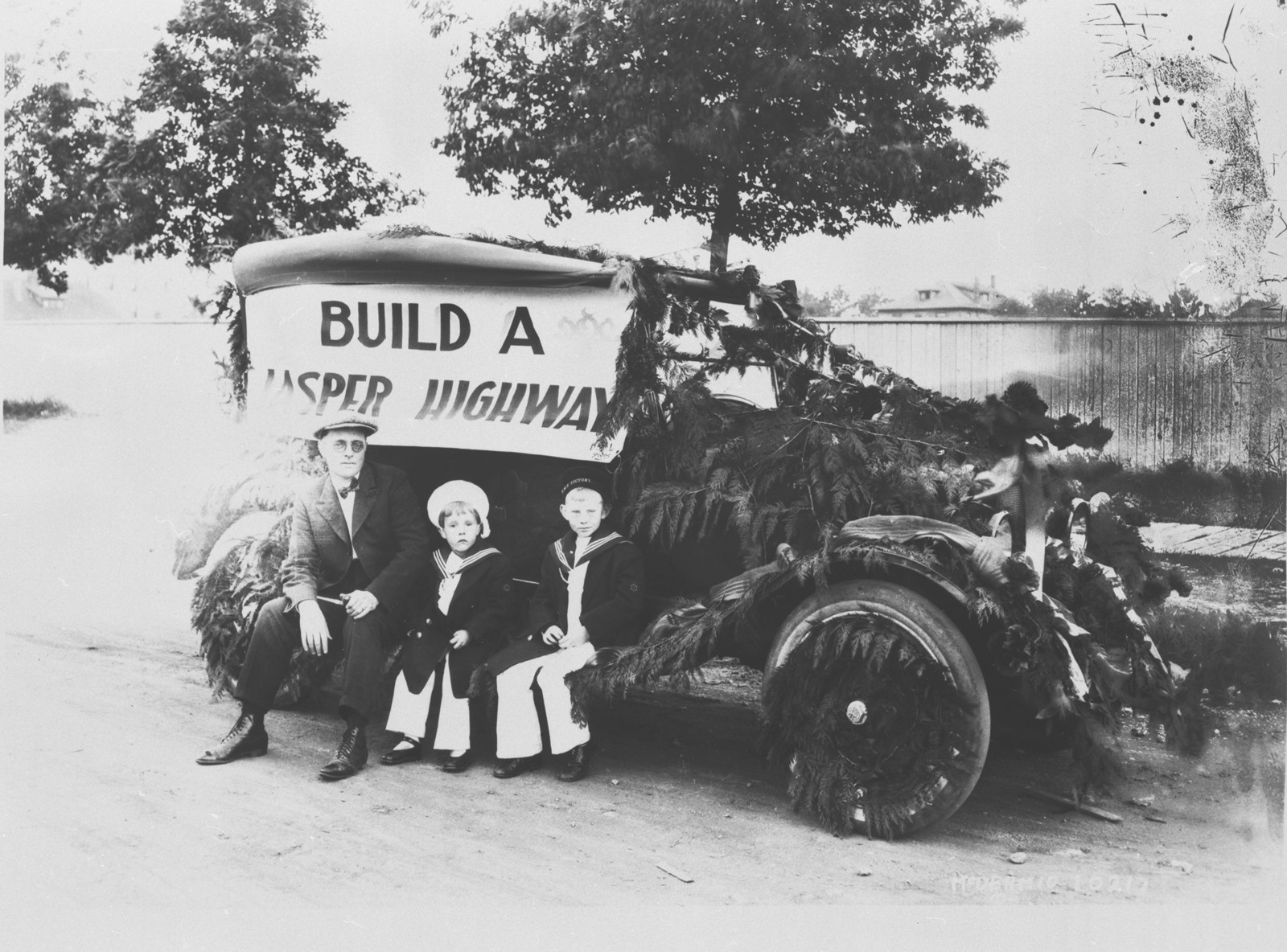 People Sitting on Old Car with Sign
