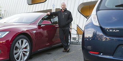 Electric vehicle owner posing with car