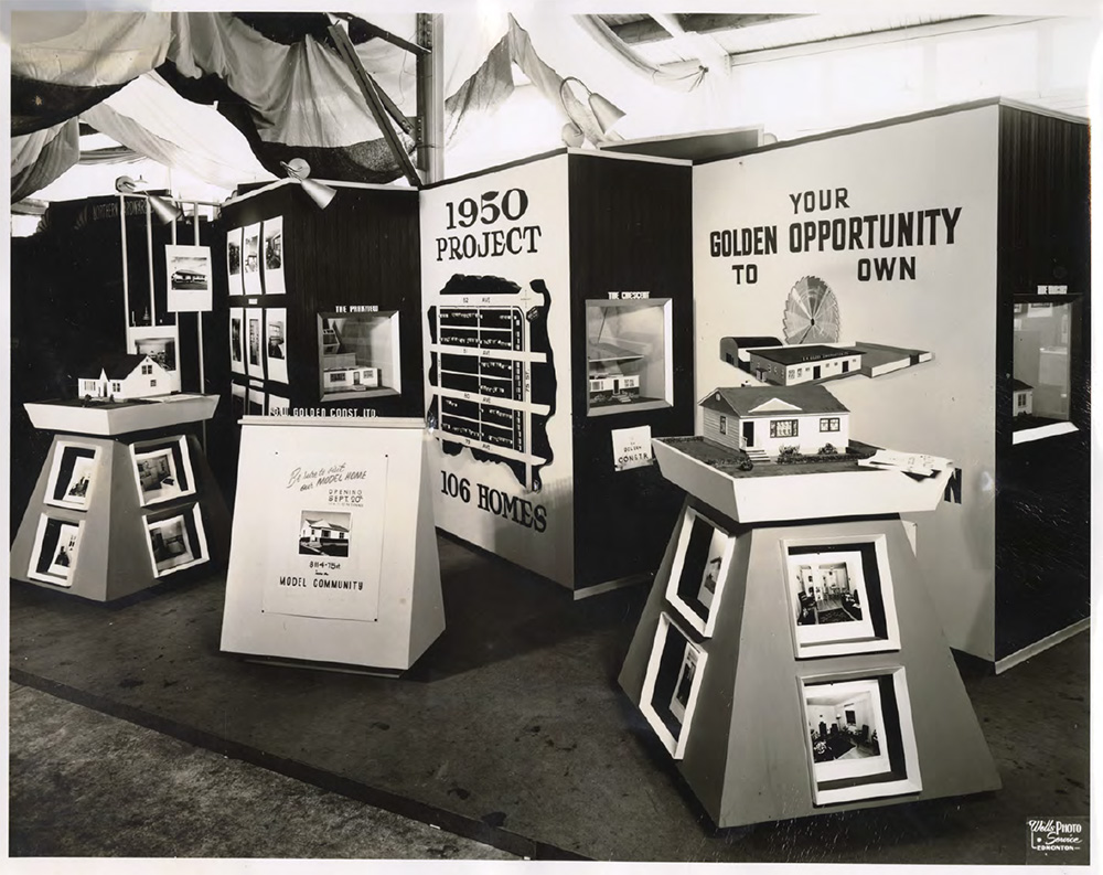 Black and white photo: a display featuring several small models of houses with yards. Posters in the background say: 1950 Project. 160 Homes. Your golden opportunity to own.