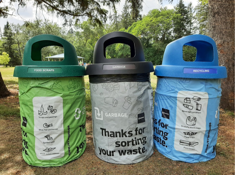 Three waste bins at picnic sites. One green, one black, and one blue.