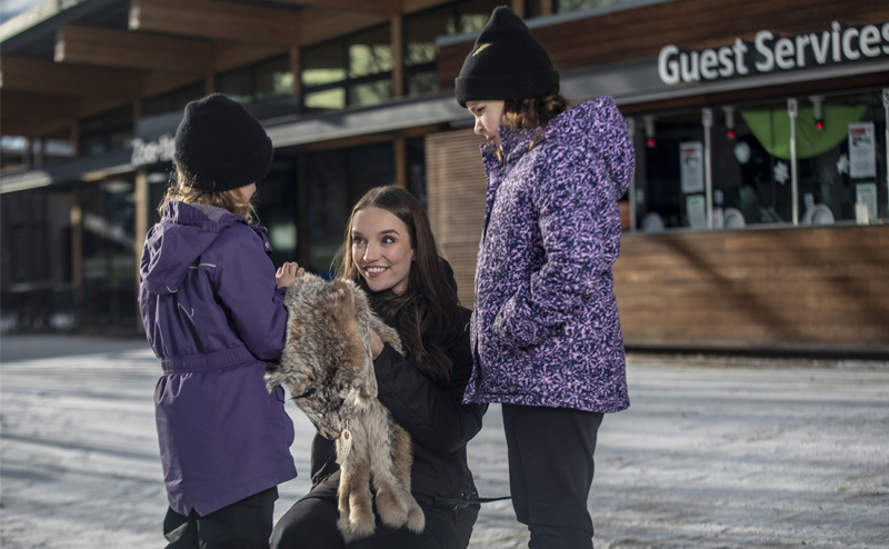 A Zoo interpreter showing two children an animal fur.