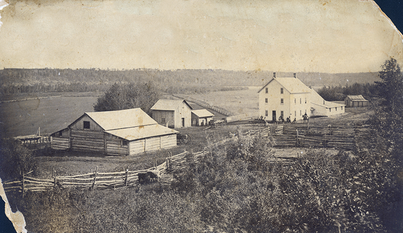 Black and white photo of the Donald Ross Homestead, surrounded by a wooden fence.