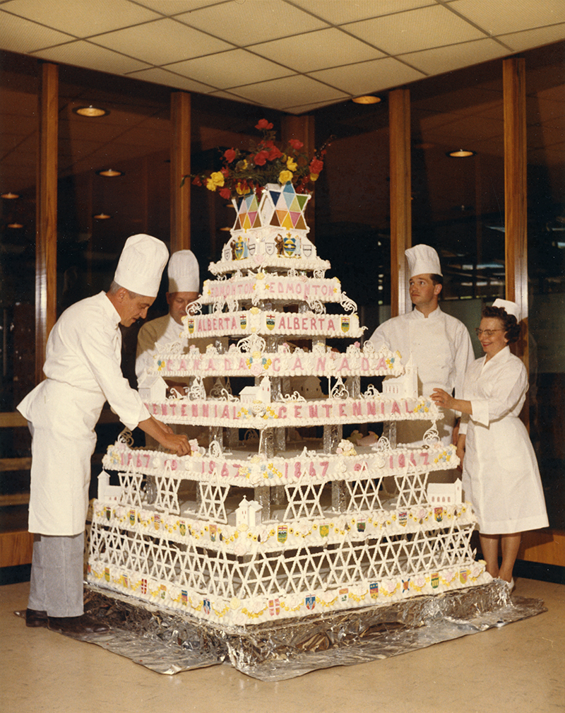 Colour photo - Three men and a woman put the finishing touches on NAIT's Centennial cake.