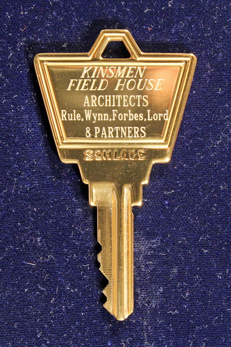 Colour photo of a key. The engraved text reads "Kinsmen Field House Architects Rule, Wynn, Forbes, Lord & Partners"