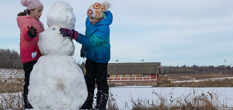 Kids building a snowman at the Northeast River Valley Park