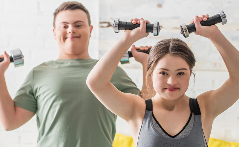 A man and a woman with disabilities holding small dumbbells.