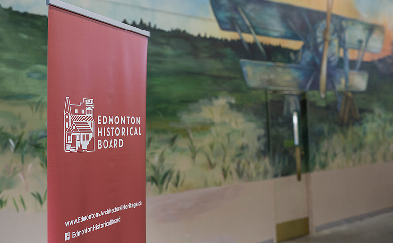 Photo of a red signpost displaying the Edmonton Historical Board logo in white. 
