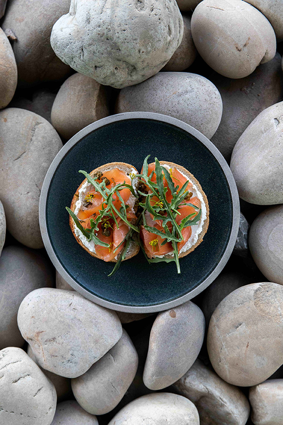 Artistic photo of bruschetta on a plate. The plate is set upon rocks.