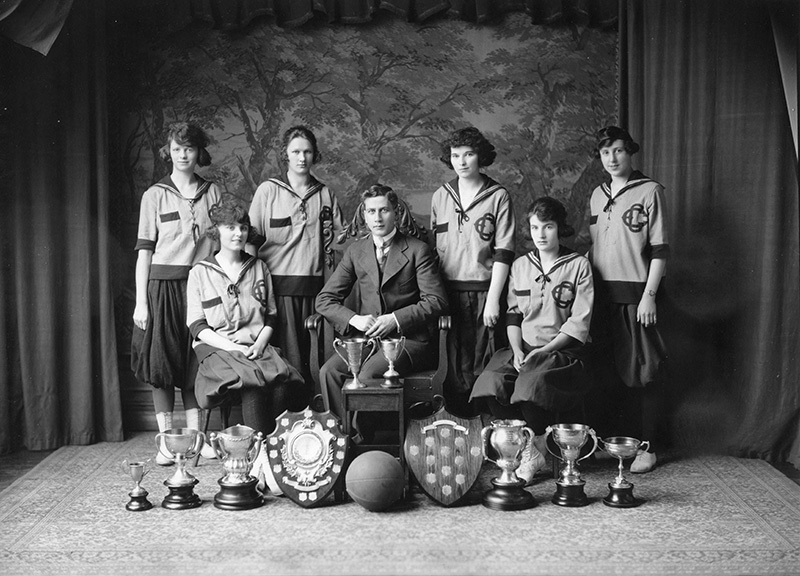 Black and white photo of the Edmonton Grads, Coach Percy Page, and several awards.