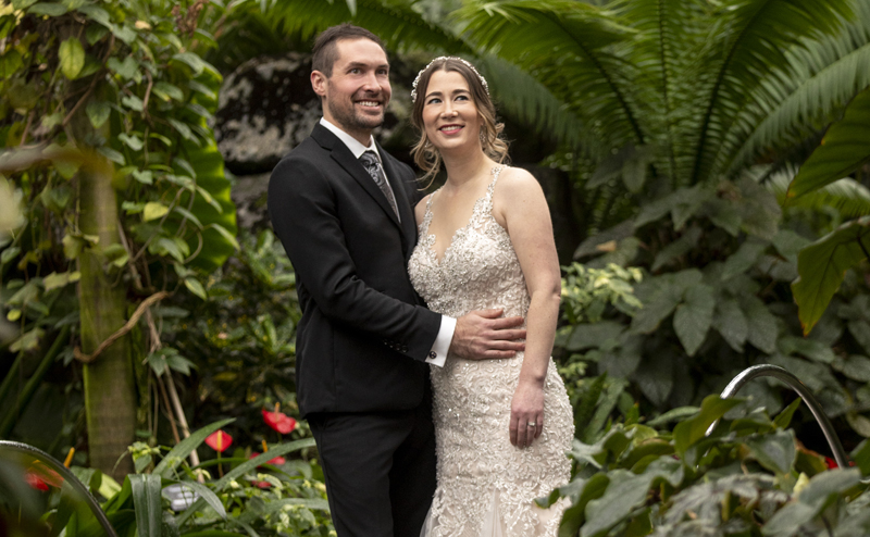 A man and a woman in wedding attire with Muttart plants in the background.