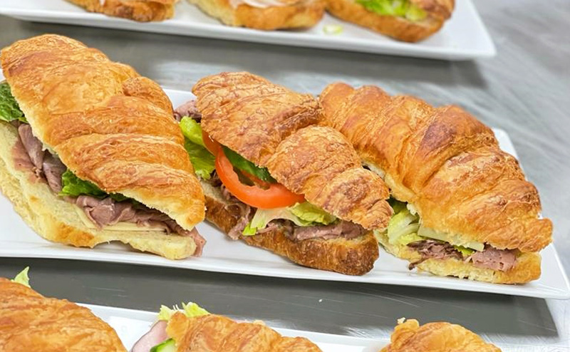 Croissant sandwiches on rectangular plates.