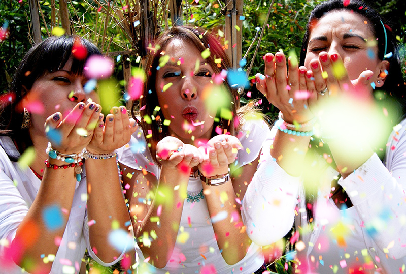Two women blowing colourful confetti