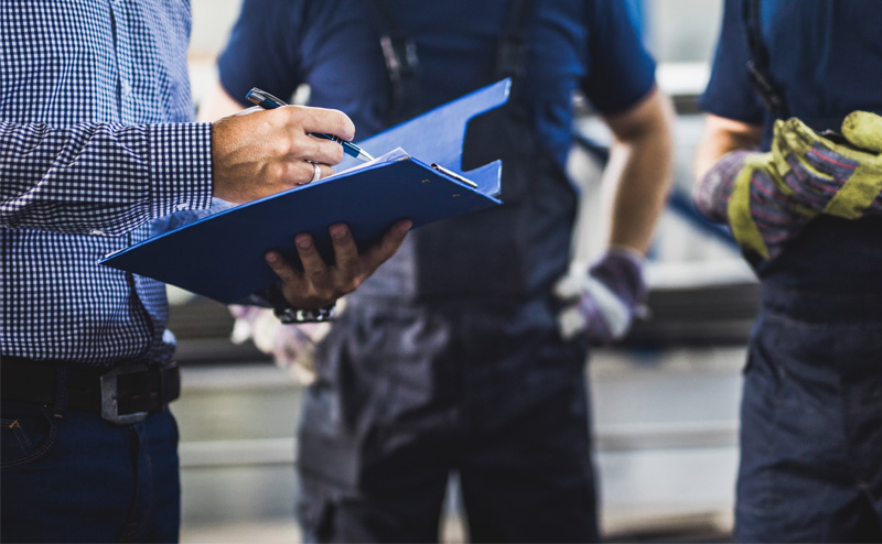 Person with a clipboard with two workers