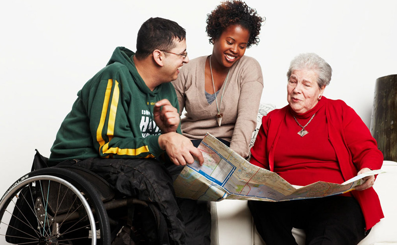 Three people looking at a printed map, one is in a wheelchair
