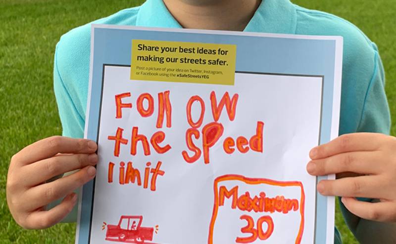 kid holding vision zero school signage