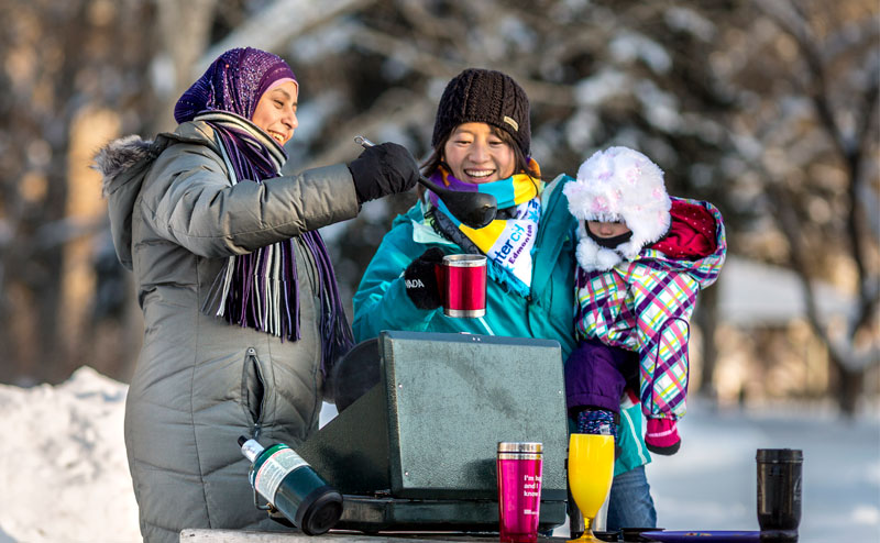 A family in warm clothes having a picnic in the winter.