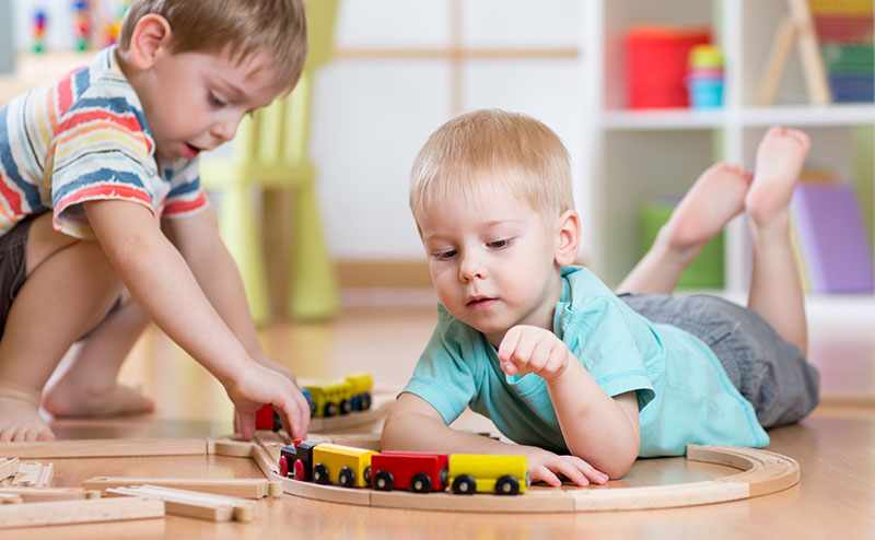 Two children playing with toy trains.