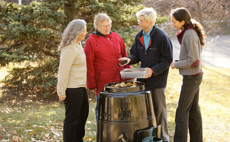 Several people gathered around a compost bin