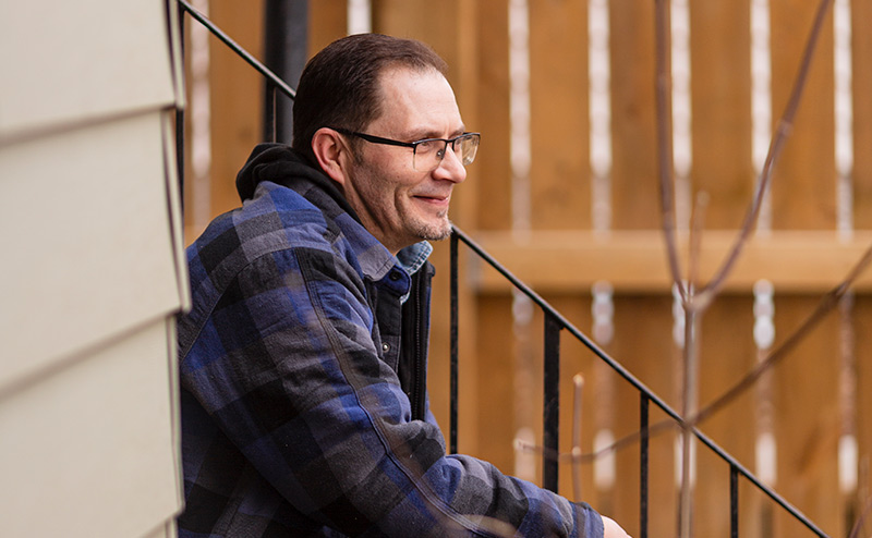 adult person sititng on doorstep smiling