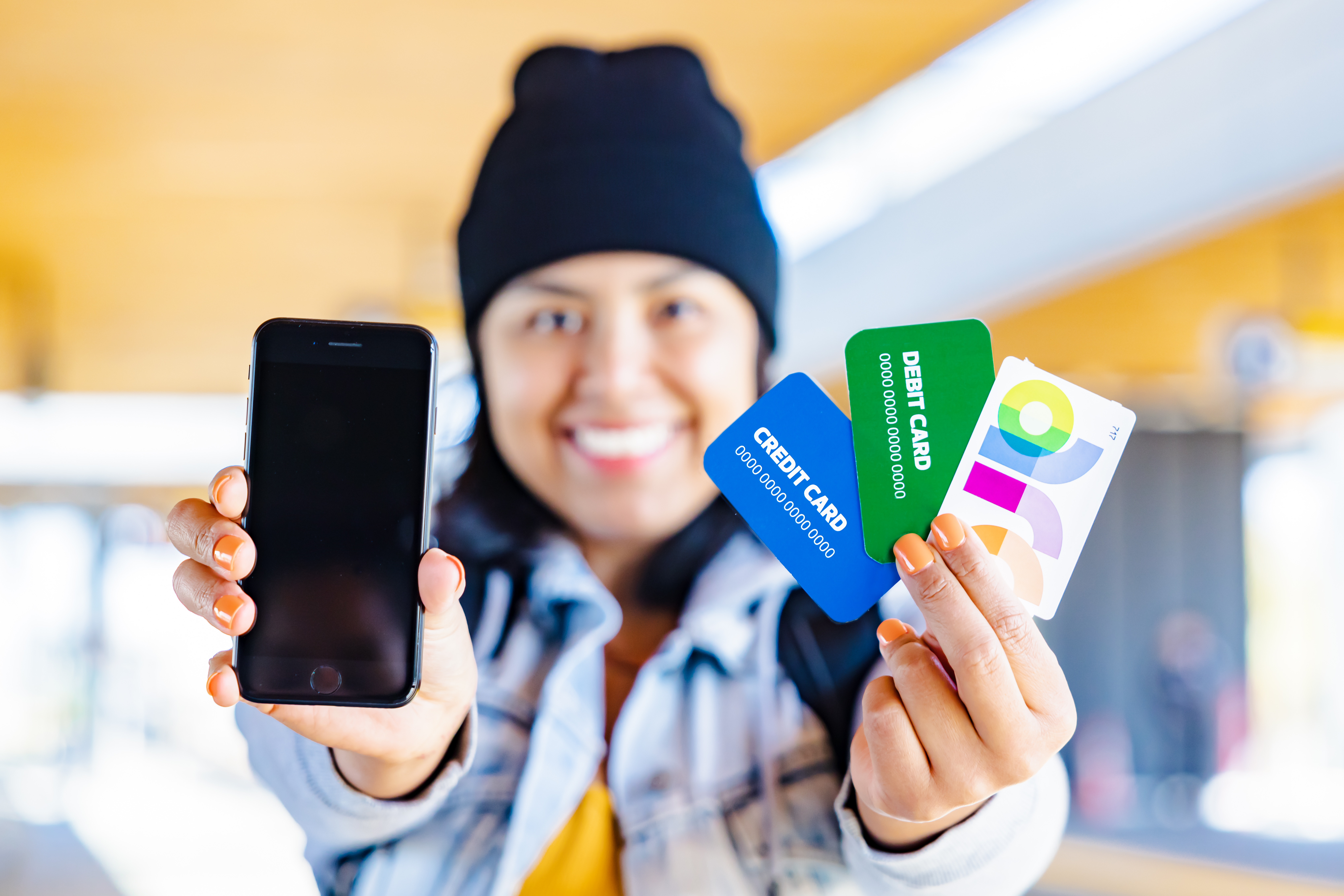 Person smiling, showing a phone, arc card, debit and credit card. 