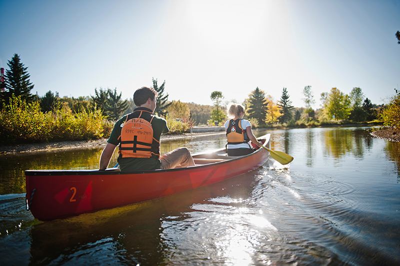 A man and a woman in a canoe on a river.