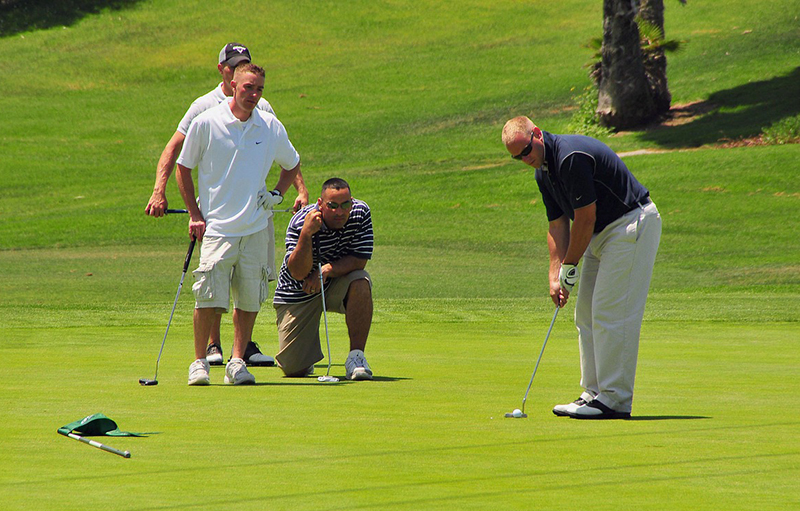 Golfer making a putt with the other players watching intently