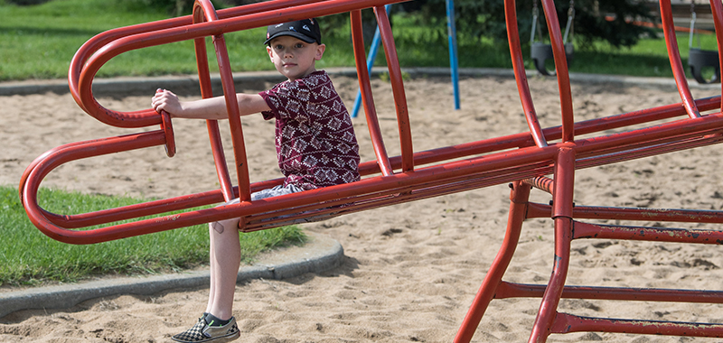 A child sitting on playground equipment in a playground.
