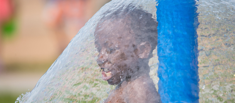 Young boy standing under a waterfall feature