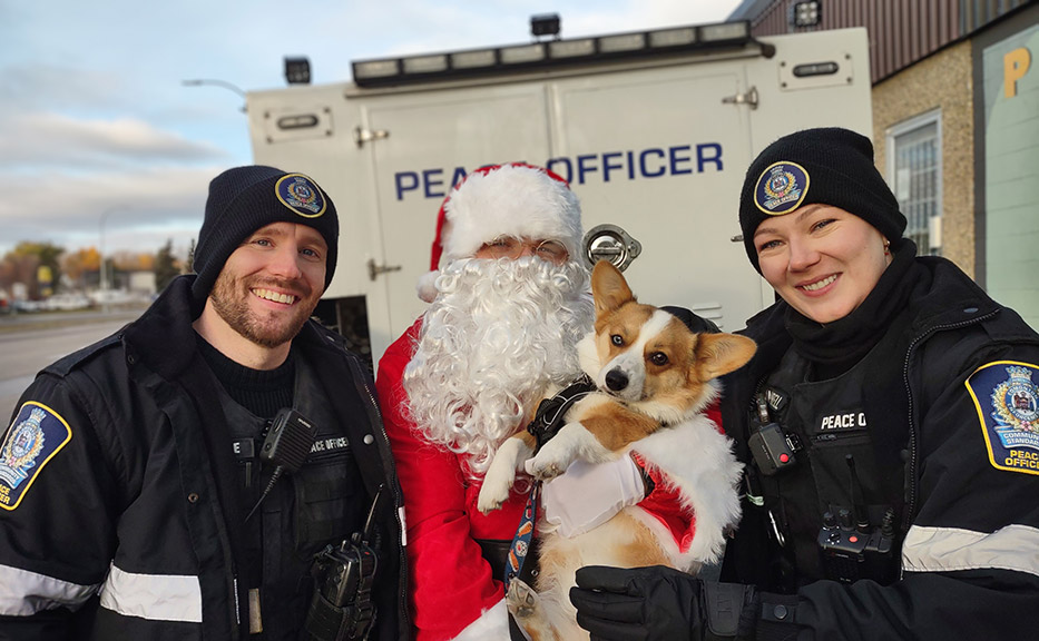 two officers with santa and a corgi