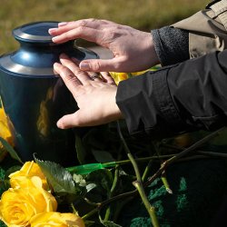 hand on casket with yellow roses