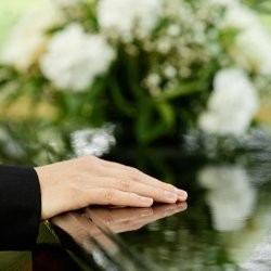 hand on casket with yellow roses