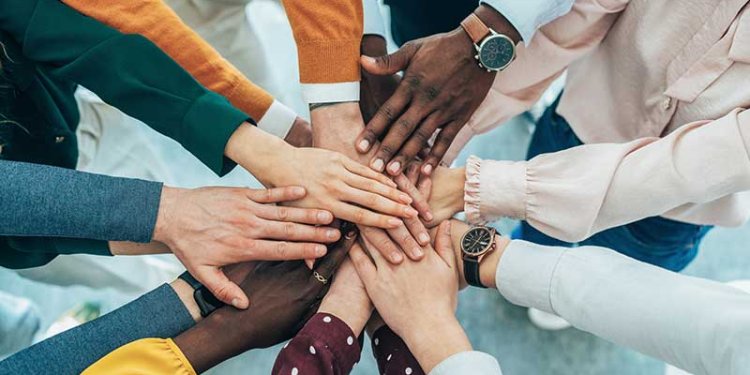 diverse people in circle touching hands