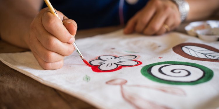 person painting red outline of flower with paintbrush