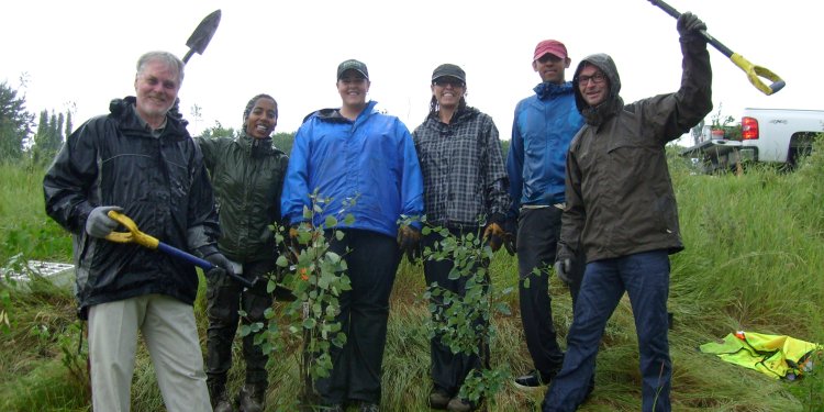 5 persons standing in park with shovels