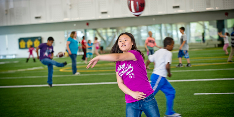 person throwing pigskin ball in field house