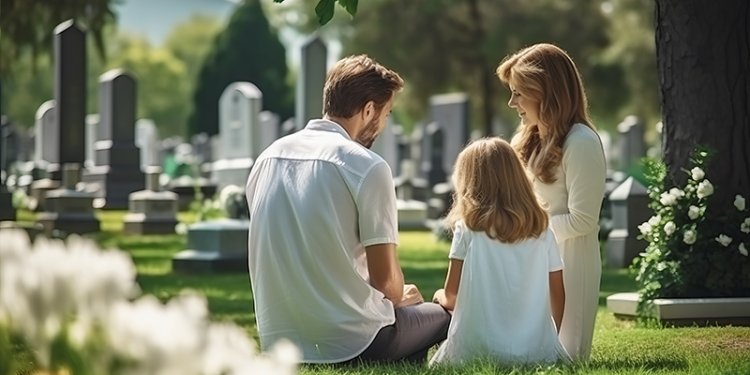 family sitting amoung gravestones in cemetery