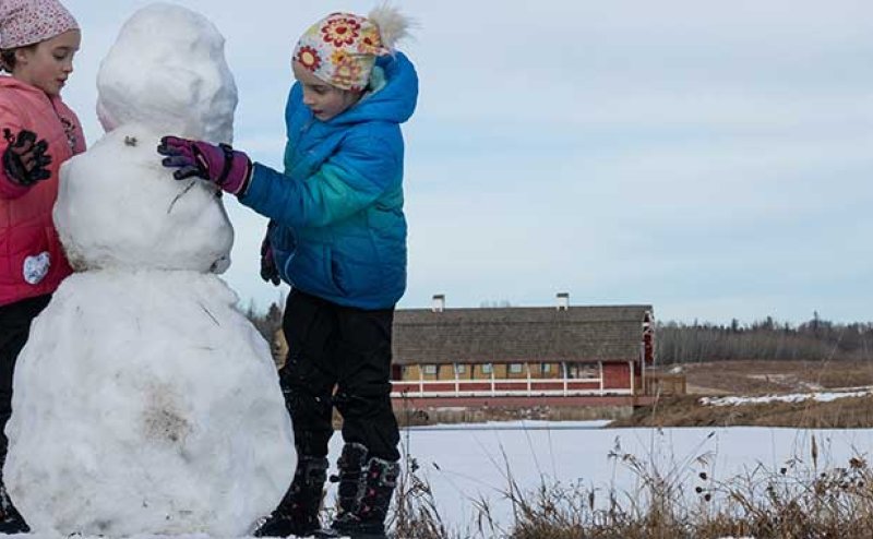 Kids building a snowman in Northeast River Valley Park.
