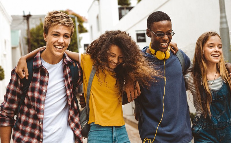 four diverse teens huddling together