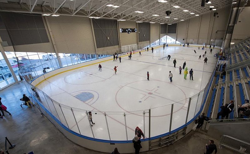 persons playing hockey on indoor ice surface