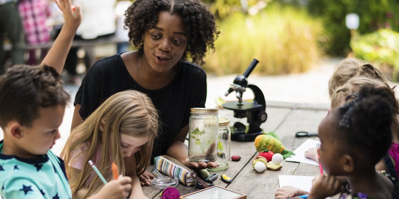 adult sitting at table with kids crafting
