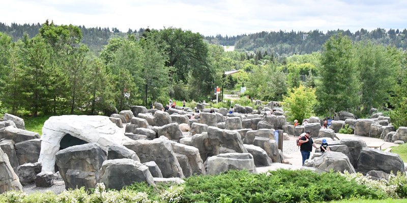 The existing Meltwater Play Area at the Zoo. Many large rocks with kids playing on and around them.