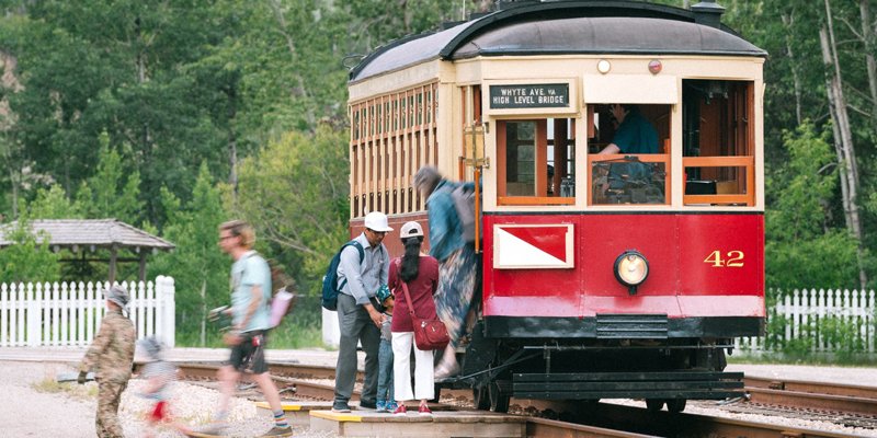 People getting off a train while a person in a period military outfit stands nearby.